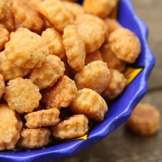 a blue bowl filled with tater tots sitting on top of a wooden table