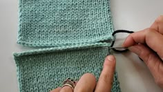 someone cutting through the ends of a knitted scarf