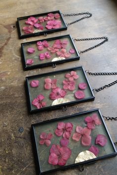 three framed pictures with pink flowers in them on a wooden table next to a black chain