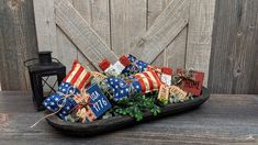 a basket filled with patriotic gifts sitting on top of a wooden table next to a lantern