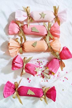 four pink and gold hair bows on top of a white sheet with confetti sprinkles