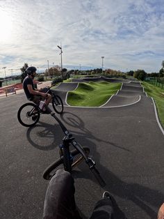 a man riding a bike down a street next to a skateboard park with ramps