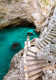 a woman is standing on some stairs by the water