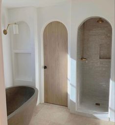 a bath tub sitting in the middle of a bathroom next to a wooden door and window