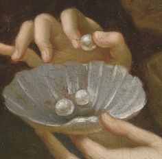 two hands holding a shell with pearls in it and another hand reaching for the shell