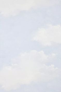 a group of people standing on top of a lush green field under a cloudy blue sky