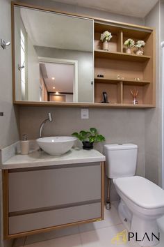 a white toilet sitting next to a sink in a bathroom under a mirror above it