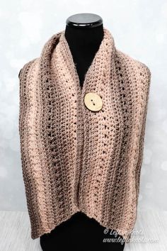 a crocheted vest with a button on the front and side, sitting on a mannequin head