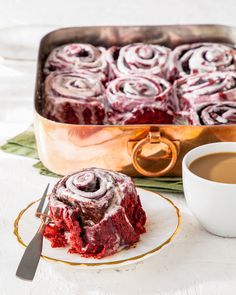 a piece of red velvet cake on a plate with a fork and cup of coffee