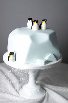 three penguins on top of a white cake