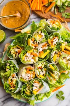 a plate filled with lettuce and carrots next to some dipping sauce