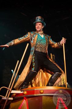 a man dressed in an elaborately designed outfit on stage with his arms out and hands outstretched