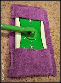 a green and white mop sitting on top of a purple towel next to a pink sponge