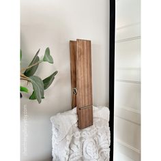 a wooden clock mounted to the side of a white wall next to a potted plant