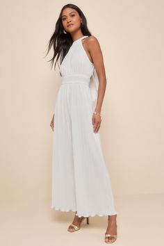 Shake up your event-ready looks with a picture-perfect outfit like the Lulus Flawless Mindset Ivory Satin Plisse Tie-Back Jumpsuit! Plisse-pleated woven satin shapes this elevated jumpsuit with a modified halter neckline (with back loop-button closures) and a fitted bodice with a smocked, banded waist. Relaxed, wide pant legs end at full length hems. Turn around to reveal a back cutout with a tying sash bow for an extra-femme finish! Elastic at back. Fit: This garment fits true to size. Length: Homecoming Jumpsuit, Chic White High-waist Jumpsuits And Rompers, Elegant White V-neck Jumpsuit, White V-neck Jumpsuit With Ruffles, White V-neck Jumpsuit With Tie Waist, White Stretch Wide-leg Jumpsuit, Bachelorette Party Dress, Adhesive Bra, Halter Jumpsuit