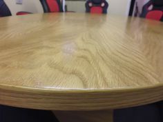 a wooden table with red chairs in the back ground and a white wall behind it