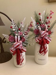 two mason jars decorated with candy canes and greenery