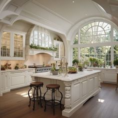 a large kitchen with white cabinets and an island in front of two windows that look out onto the woods