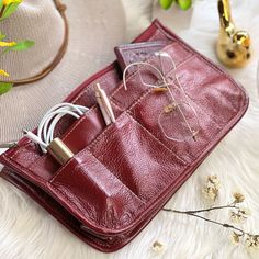 a red leather case with ear buds and wires in it sitting on a white furnishing