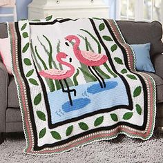 two flamingos are standing in the water on a blanket