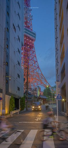 people are riding bicycles down the street in front of a tall tower