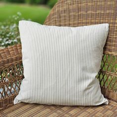 a white pillow sitting on top of a wicker chair