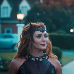 a woman dressed as catwoman standing in front of a house with her eyes closed