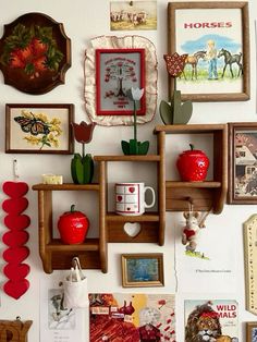 the wall is covered with many different pictures and framed art pieces, including red apples