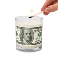 a hand holding a match stick over a money candle