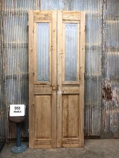 an old wooden double door next to a trash can