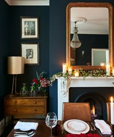 the dining room table is set for dinner with candles and flowers in front of it