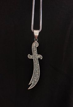 Zulfiqar Arabic Written Islamic Men Necklace Due to the issues in supply, the chain that is going to be send will be a different one but very similar to the picture. You can contact us for more detail. Perfect Silver Islamic-Muslim pendant, the sword of Ali.  The sword called as Zulfiqar. It is a 925 sterling real silver and handmade. A special gift for Muslim men for birthdays and special days. If you have a question please don't hesitate to contact me. Material: 925 Sterling Silver Size: 1*6 cm-5.9cm / 0.62*2,32 in Chain Lenght :55 cm / 21.65 in Weight: 12.40 gr Story of This Meaningful Sword: Alī ibn Abī Ṭālib showed a lot of heroism in the battle of Uhud.  While trying to protect the Prophet in battle, his sword is broken.  Seeing this, our Prophet gave him his sword, Zulfikar.  With h Battle Of Uhud, Islamic Necklace, Muslim Men, Imam Ali, Men Necklace, Special Gift, Special Gifts, Valentine Day Gifts, Jewelry Necklace Pendant