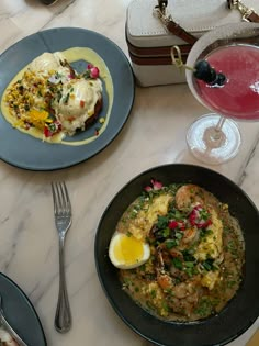 two plates of food on a table with silverware and wine glasses next to them