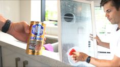 a man is opening the freezer door with an apple in his hand and holding a can of beer