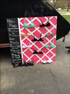 a chalkboard with several different types of earrings on it next to a parked car