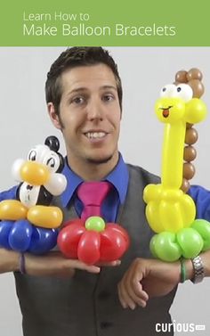 a man holding up some balloons in his hands with an animal and giraffe design on them