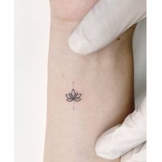 a small lotus tattoo on the left side of the arm, with dots in it