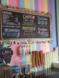 a chalkboard menu hangs on the wall behind a coffee shop counter with colorful striped walls