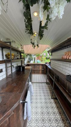 the inside of a restaurant with lots of counter space and flowers hanging from the ceiling