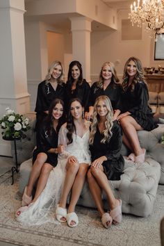 a group of women sitting on top of a couch in front of a chandelier