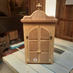 a wooden cabinet sitting on top of a table next to a building with windows and doors