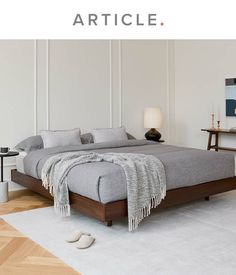 a large bed sitting on top of a wooden floor next to a white rug and table