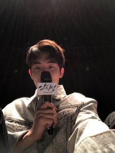 a man holding a microphone in front of his face with the words exo written on it