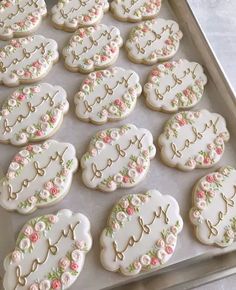 there are many decorated cookies on the baking sheet in the pan, one is white and has pink flowers