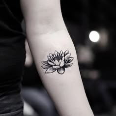 a woman's arm with a black and white lotus tattoo on the left forearm