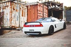 a white sports car parked in front of a shipping container