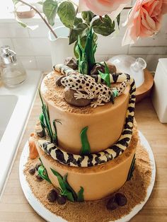 a three tiered cake is decorated with leopards and geckos on top