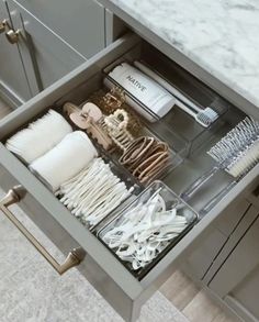 an open drawer in a kitchen filled with white utensils and other items on the counter