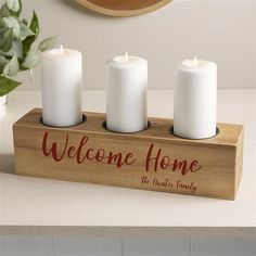 three white candles sitting on top of a wooden box