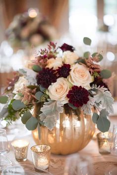 a vase filled with white and red flowers on top of a table next to candles